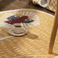 Yellow rug with a rooster design featuring a cup of coffee on a wooden floor.