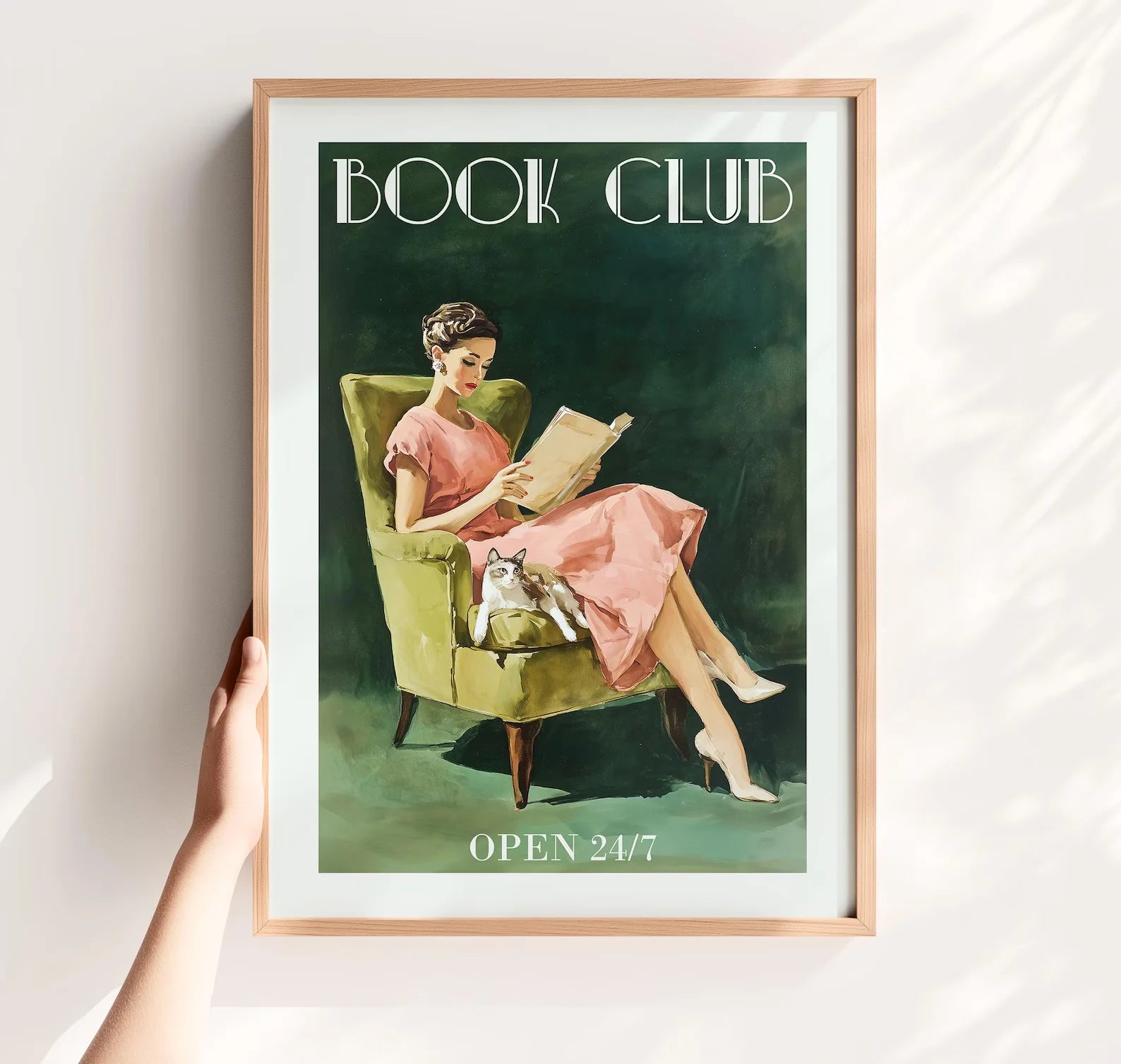 Framed artwork of a woman reading a book with text 'Book Club Open 24/7' on a white wall.