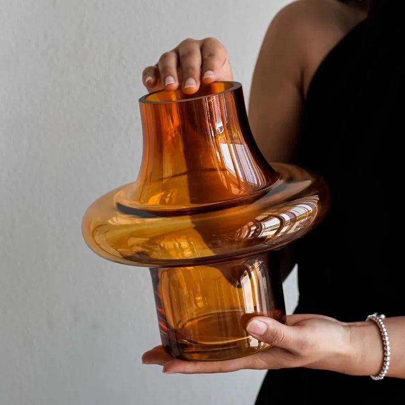 Person holding a large amber-colored glass object against a neutral background