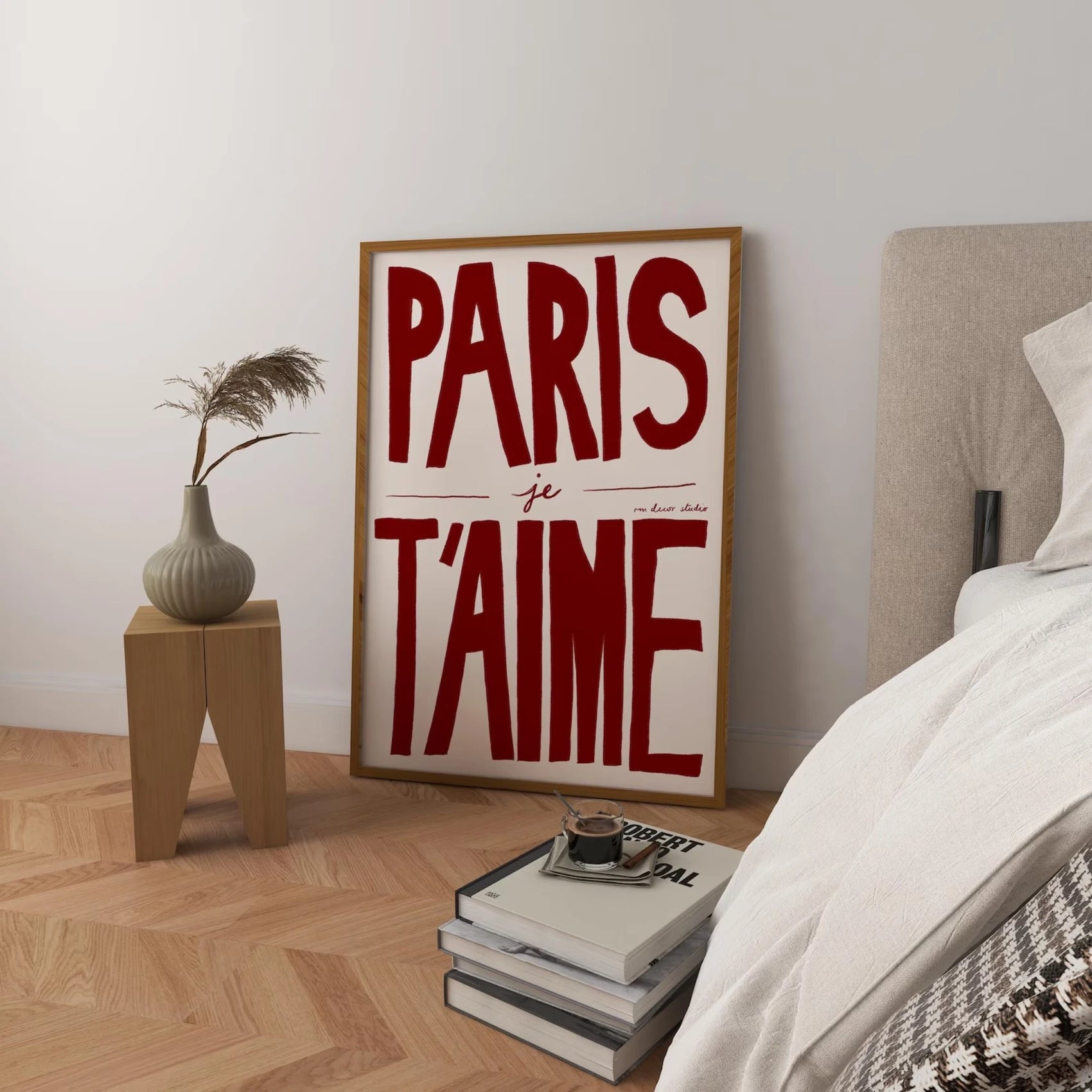 Room interior with 'PARIS je T'AIME' poster on a wall, books, and a plant.