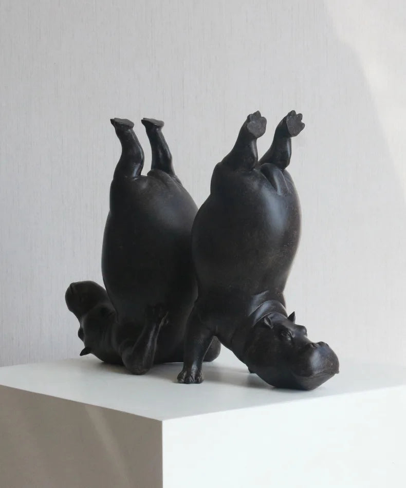Black ceramic hippo sculpture on a white surface with a light gray background