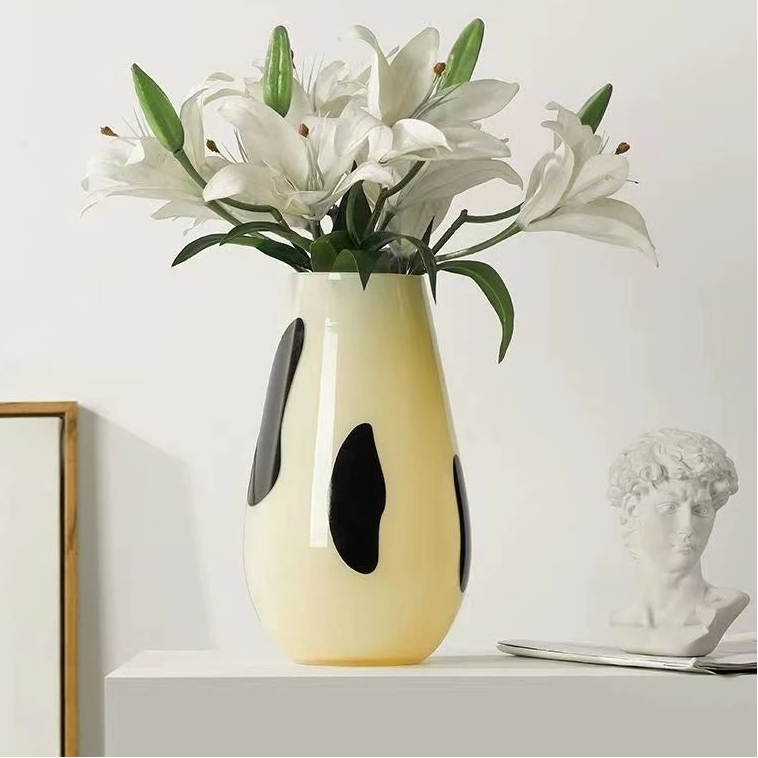 Decorative vase with white flowers on a shelf against a light background