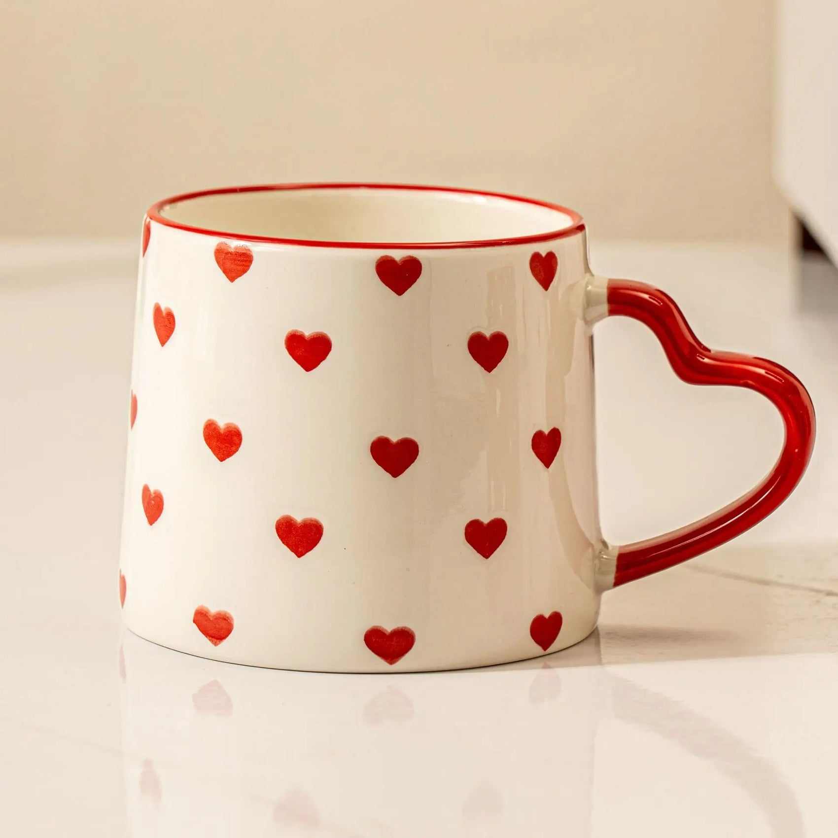 White mug with red heart patterns on a white surface