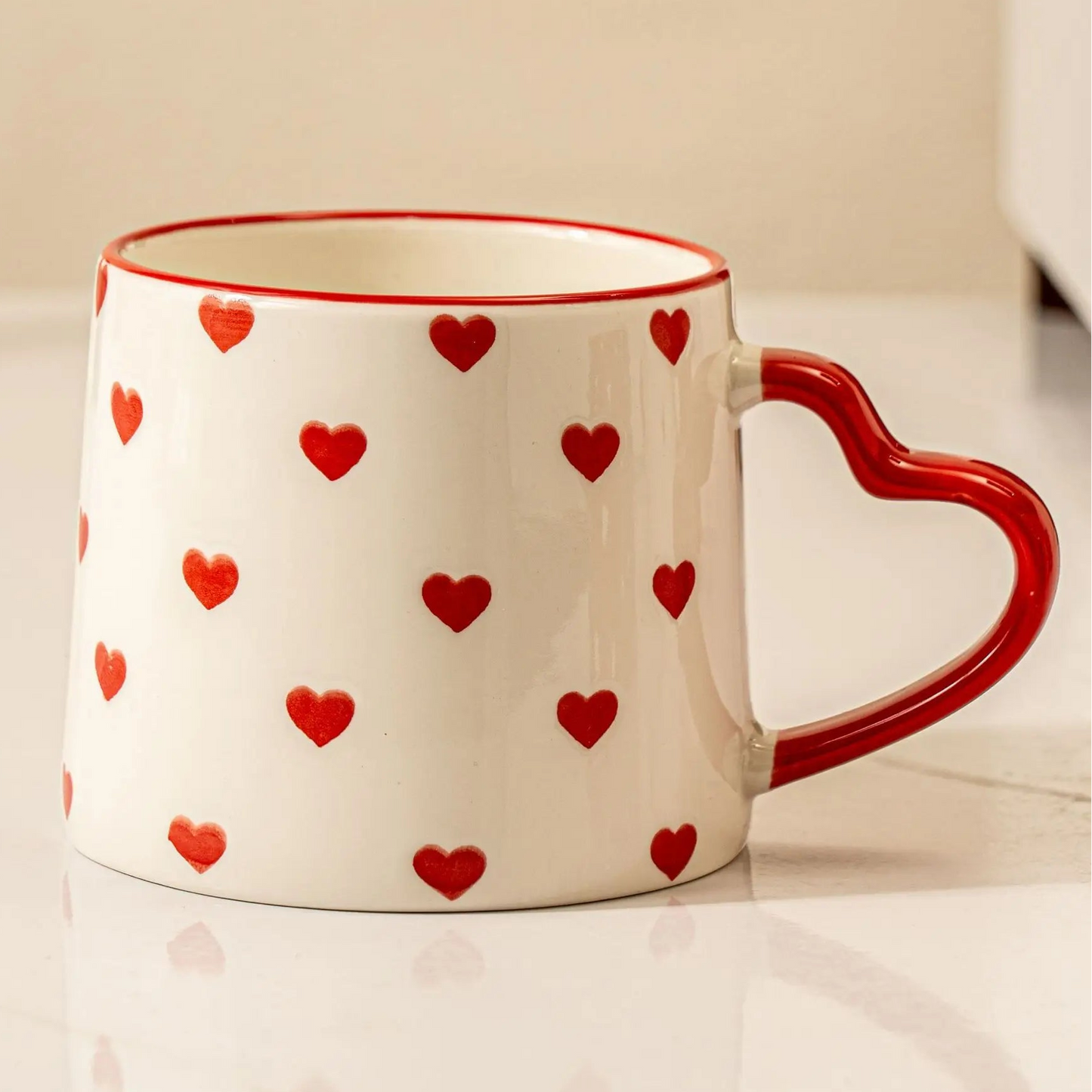 White mug with red heart patterns on a white surface