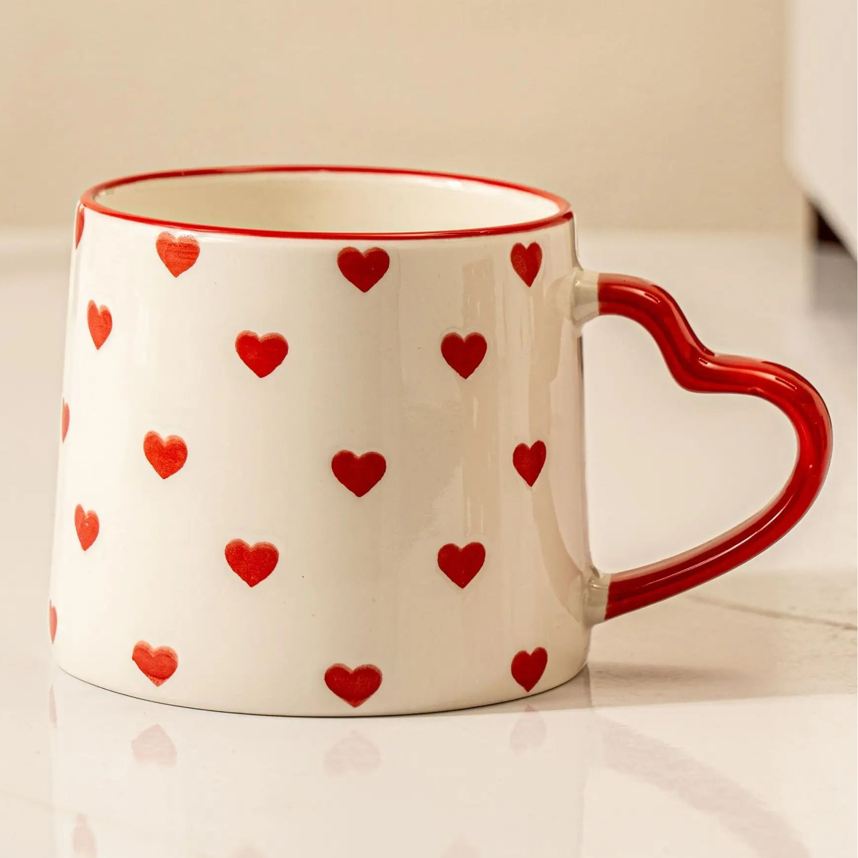 White mug with red heart patterns on a white surface