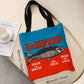 Tote bag with 'Sardines' design on a surface with a magazine and cup.