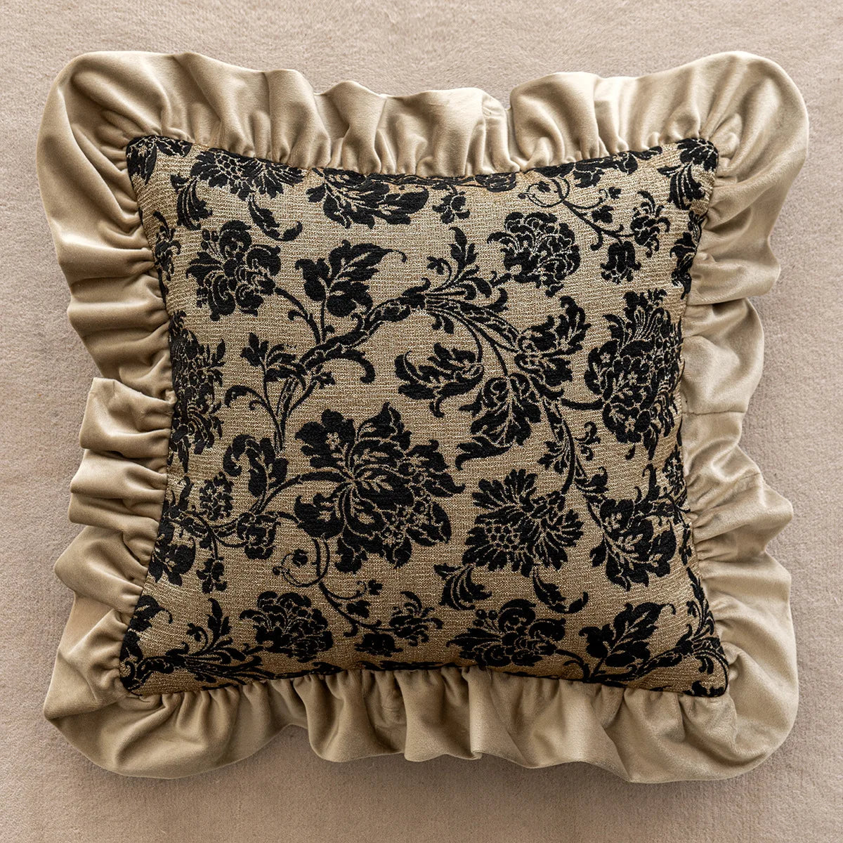 Decorative pillow with black floral pattern and beige ruffled edges on a beige background