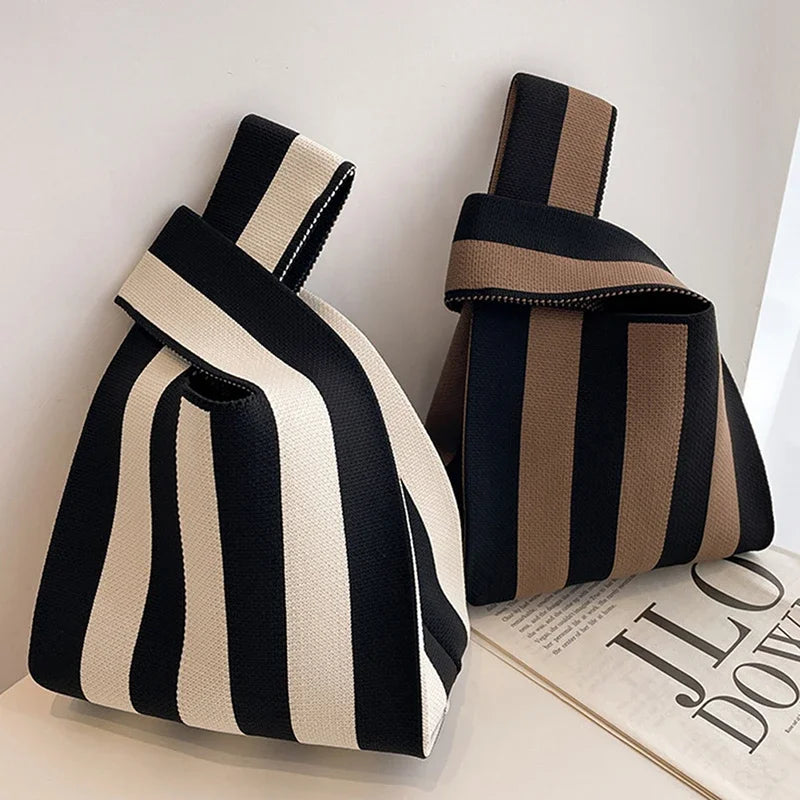 Two striped bags, one black and white, one brown and black, on a light surface with a magazine underneath.
