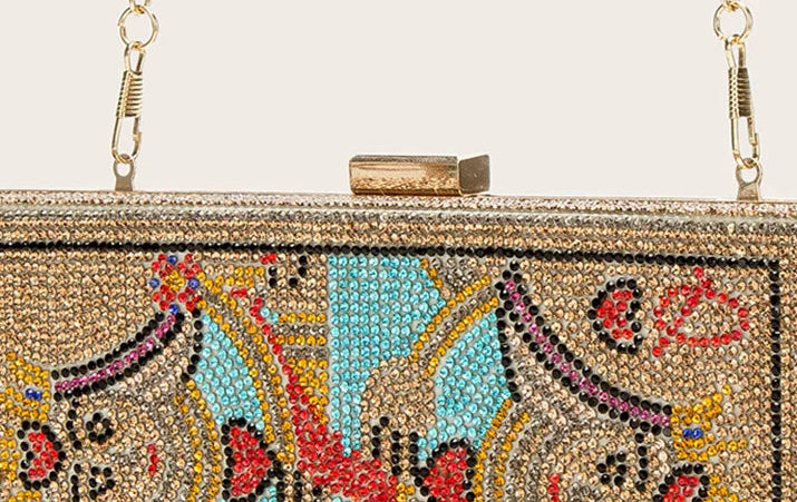 Decorative clutch bag with intricate patterns and colorful stones on a light gray background