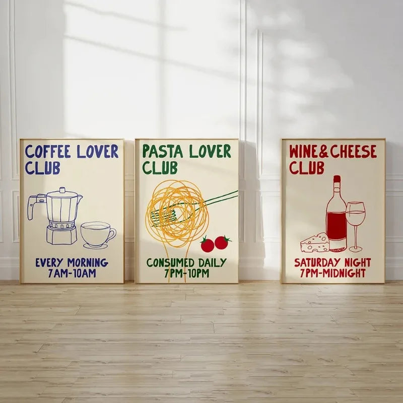 Three framed prints titled 'Coffee Lover Club', 'Pasta Lover Club', and 'Wine & Cheese Club' on a wooden floor.