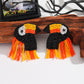 Toucan-shaped earrings with orange, black, and yellow beads on a white background.