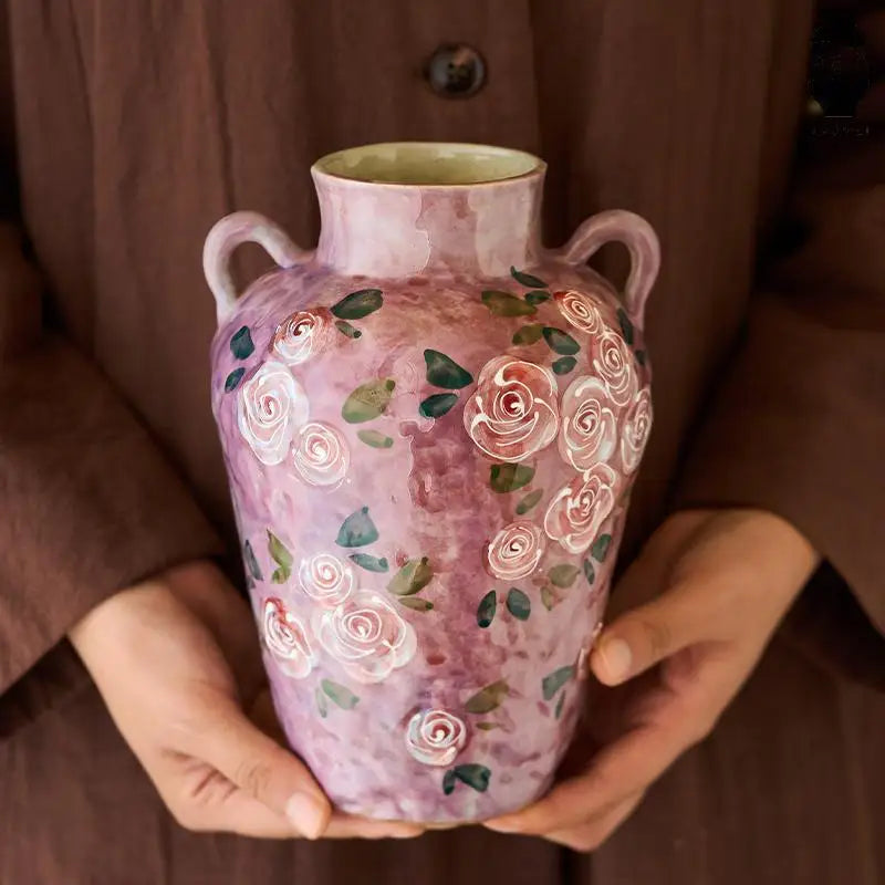 Person holding a decorative vase with floral patterns
