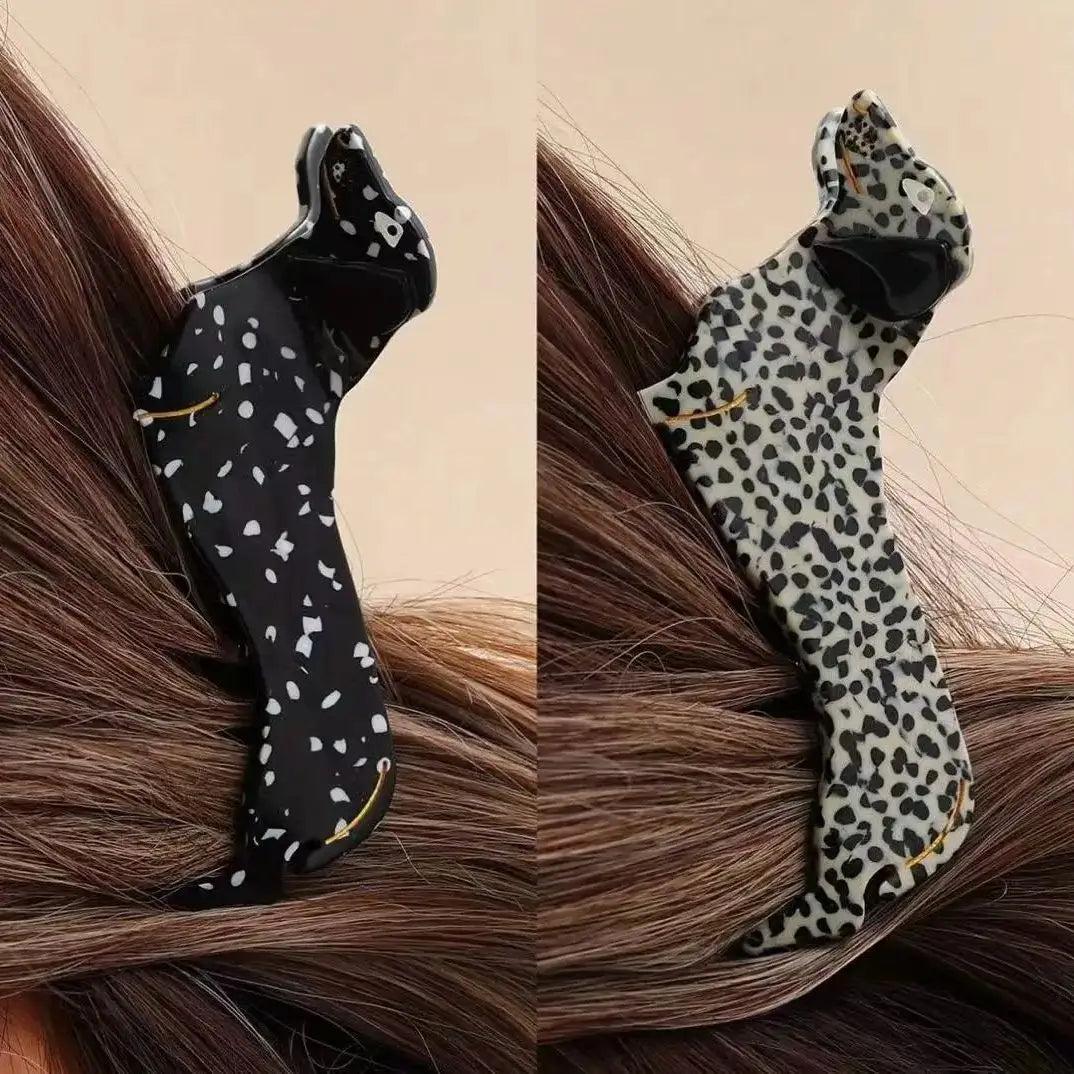 Two hair clips, one with black and white polka dot pattern and the other with leopard print, on brown hair.