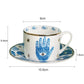 Ceramic cup and saucer with blue hand design and measurements on a white background