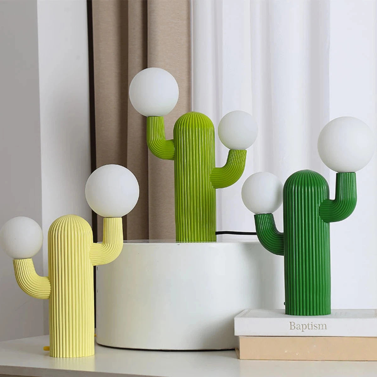 Cactus-shaped lamps in green and yellow on a shelf with a neutral background