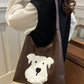 Brown tote bag with a white dog design held by a person indoors.
