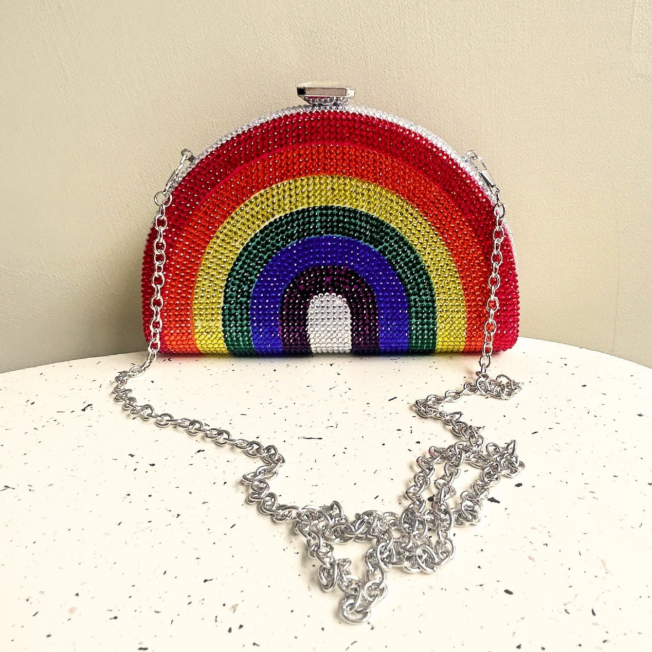 Rainbow-colored beaded handbag with a chain strap on a beige background, featuring the brand 'CEZIRA'.
