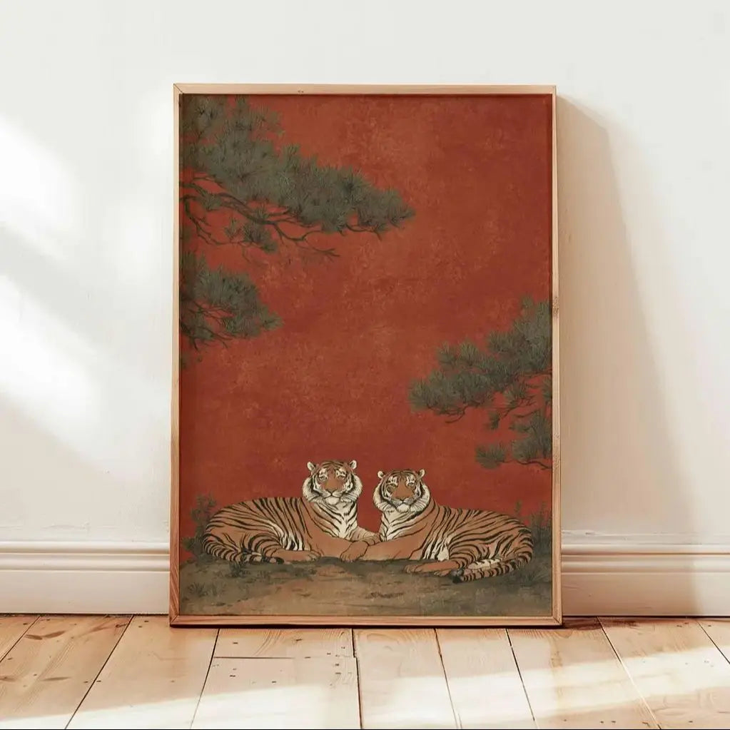 Framed artwork of two tigers on a red background with trees, leaning against a white wall.