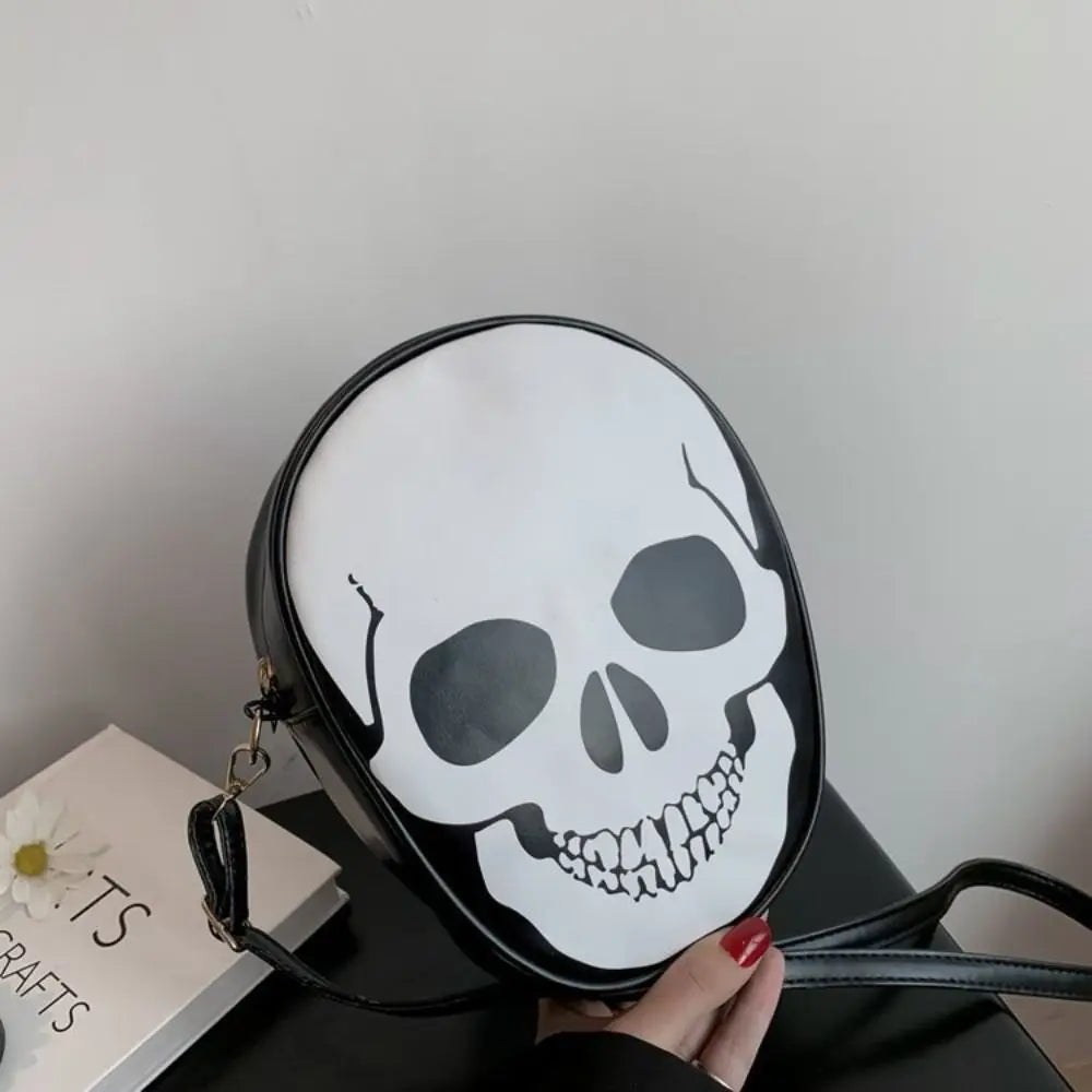 Black round bag with a white skull design held by a hand on a light gray background