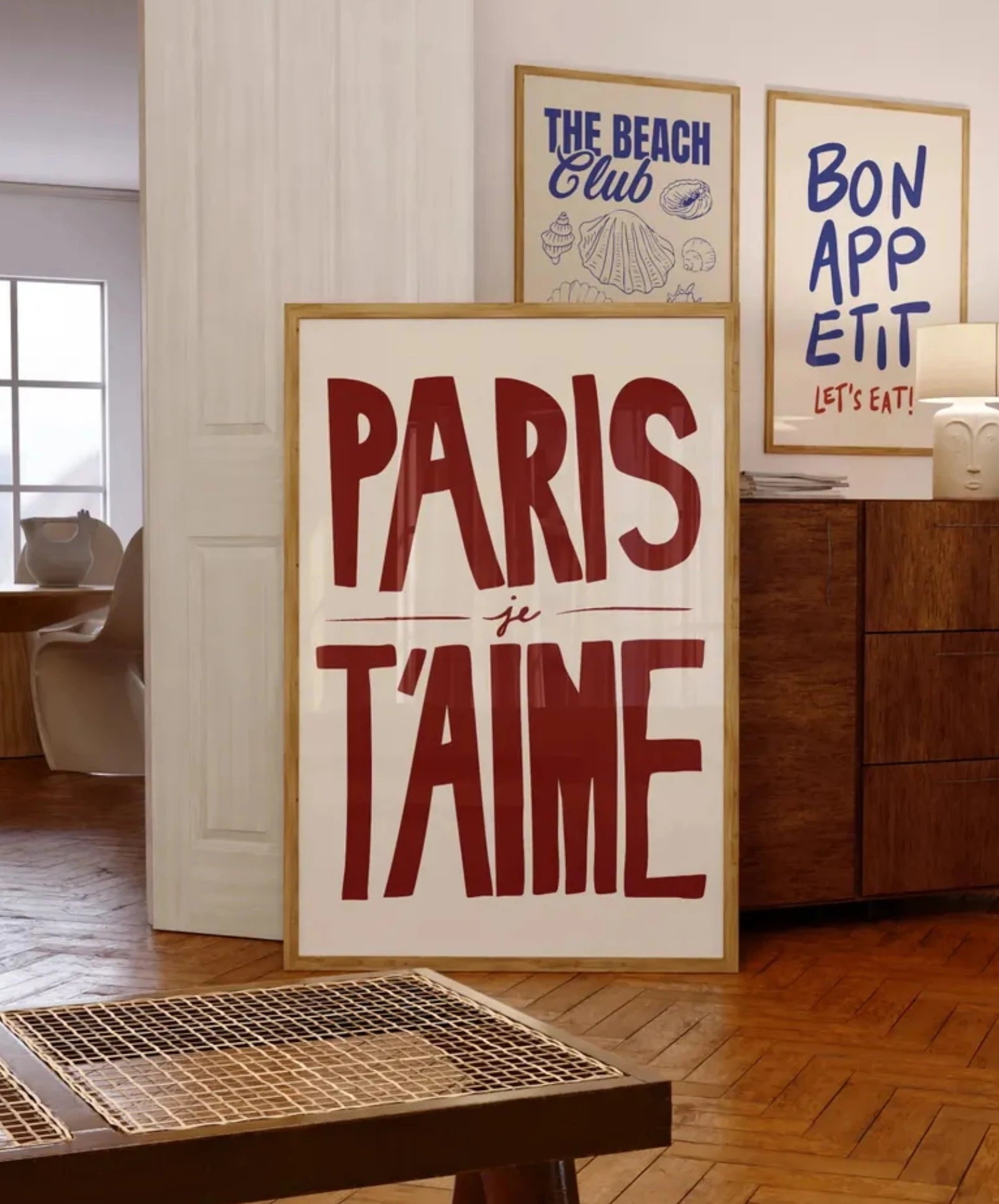 Decorative sign with 'PARIS je T'AIME' in a room with wooden furniture and framed art on the wall.