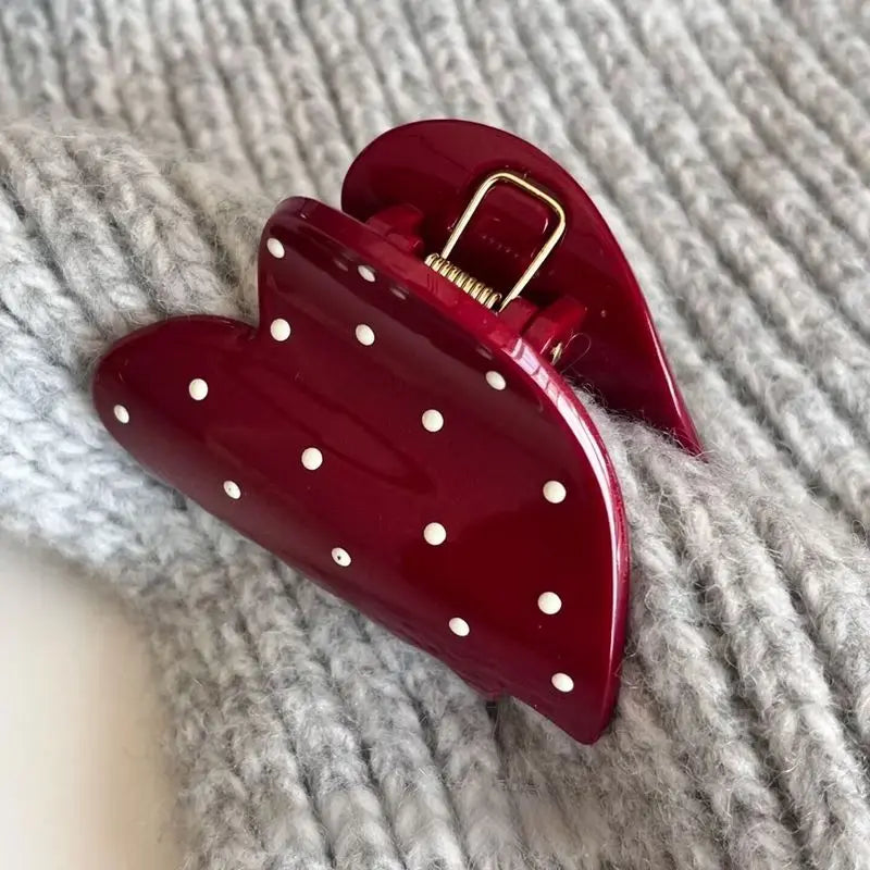 Red heart-shaped clutch with gold clasp on a textured surface