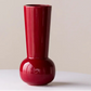 Red vase on a white surface with a beige background