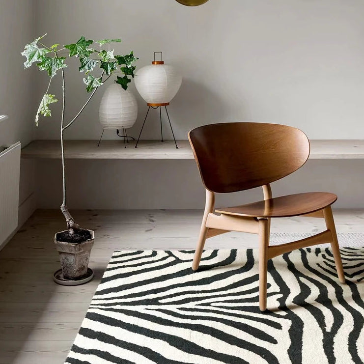Modern room with a wooden chair, zebra-patterned rug, and decorative lamps.