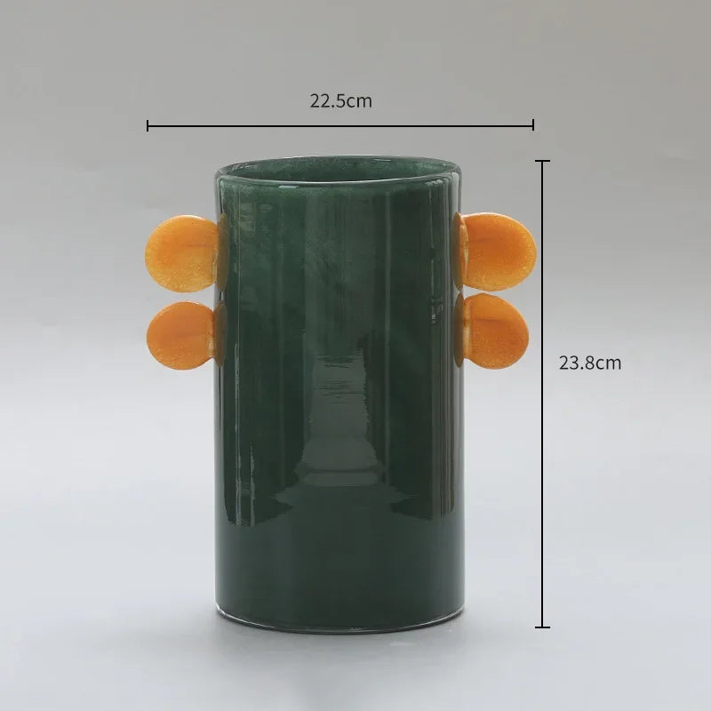 Green sculptural vase with orange circular handles for colorful interior styling