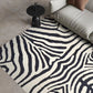 Zebra patterned rug on a beige floor with a modern sofa and side table.