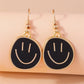 Smiley face earrings with gold frames on a beige background