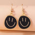 Smiley face earrings with gold frames on a beige background