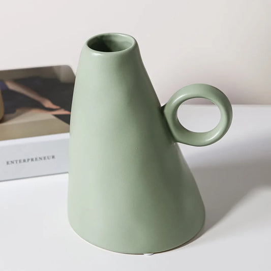 A green ceramic decorative vase with a geometric design, placed on a white surface next to a box labeled 'ENTREPRENEUR'.