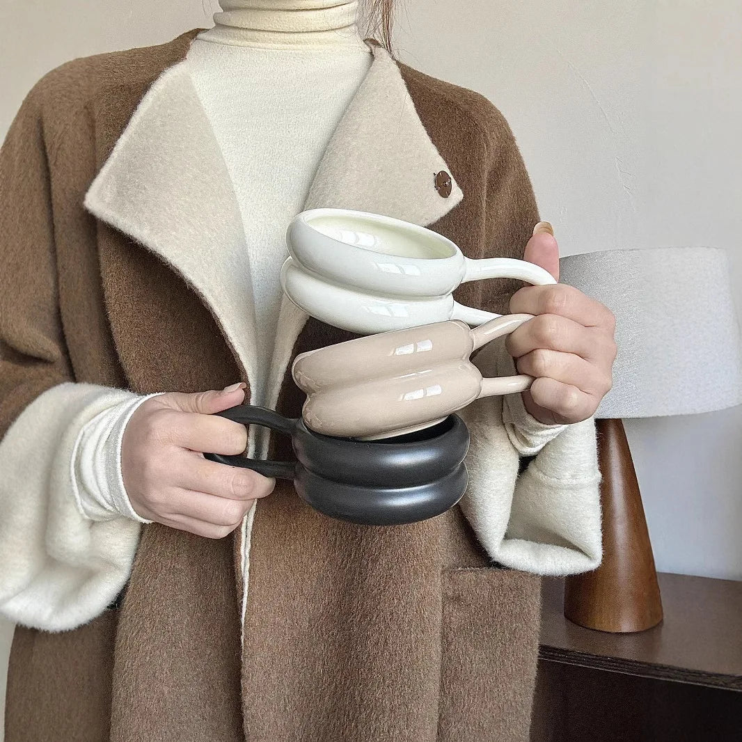 Person holding a stack of ceramic cups with a neutral background