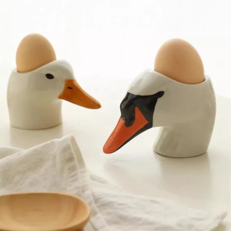Two ceramic duck-shaped egg holders with eggs on a white background