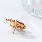 Gold earring with red stones on a white background