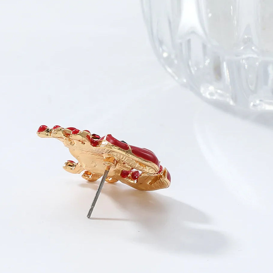 Gold earring with red stones on a white background