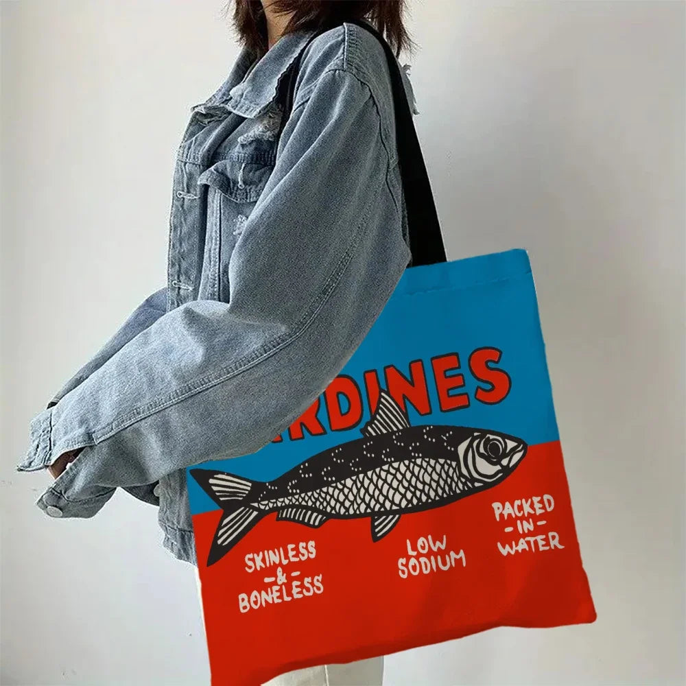 Person holding a tote bag with a fish design and text on a plain background