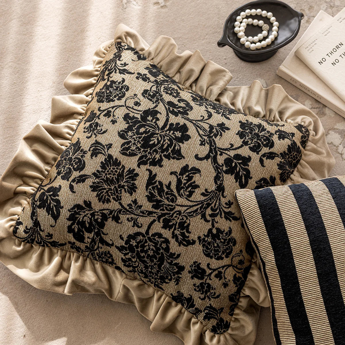 Decorative pillow with black floral pattern on beige fabric, placed on a surface.