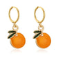 Pair of earrings with orange fruit and gold hoop designs on a white background