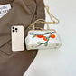 Small handbag with floral design next to a smartphone on a white surface