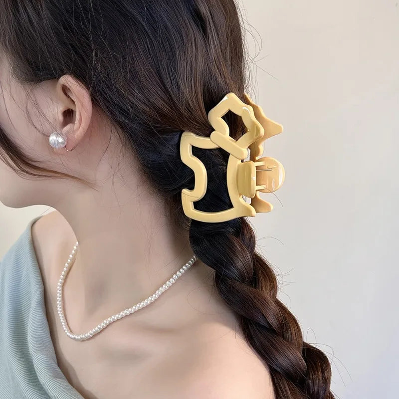 Woman with a yellow hair clip and pearl earring on a neutral background