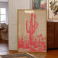 Framed artwork of a cactus with a pink desert scene in a room setting.