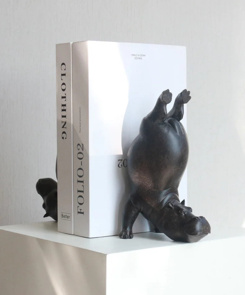 Hippopotamus-shaped bookends on a white surface with a white box labeled 'FOLIO-02' in the background.