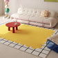Yellow abstract rug on a tiled floor with a white sofa and red table in the background.