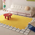 Yellow abstract rug on a tiled floor with a white sofa and red table in the background.