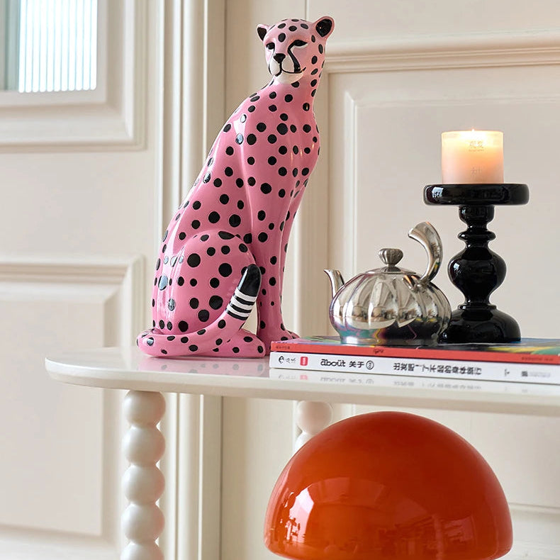Decorative ceramic cheetah on a shelf with a candle and books in a room.
