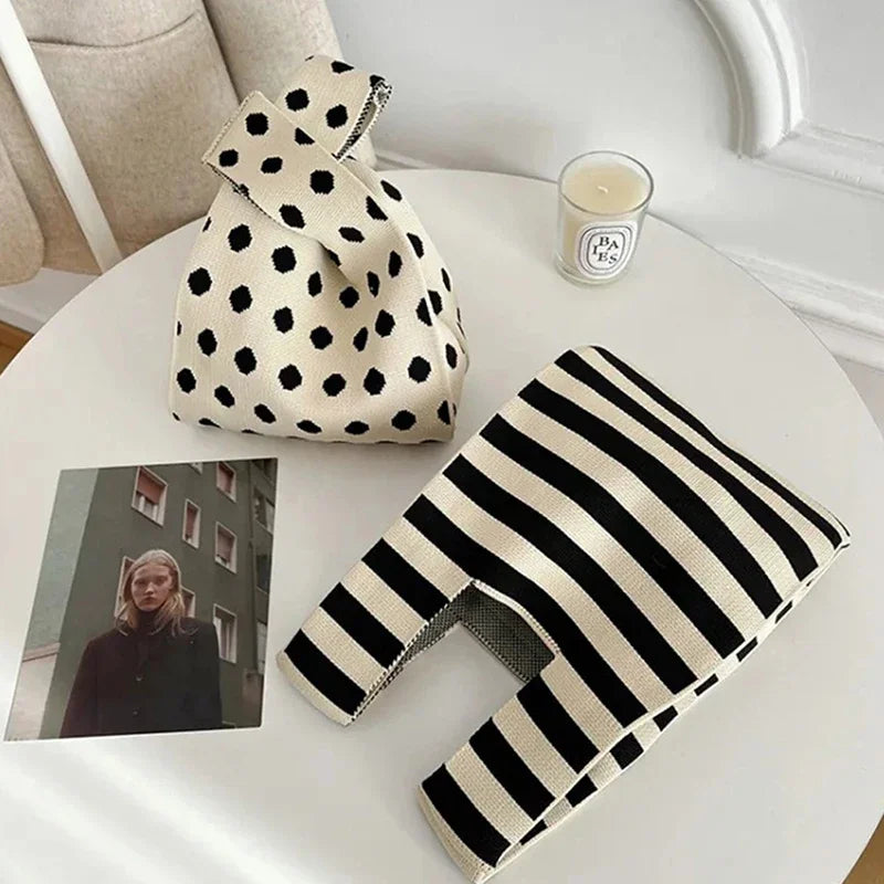 Polka dot bag and striped blanket on a white surface with a candle and photo.
