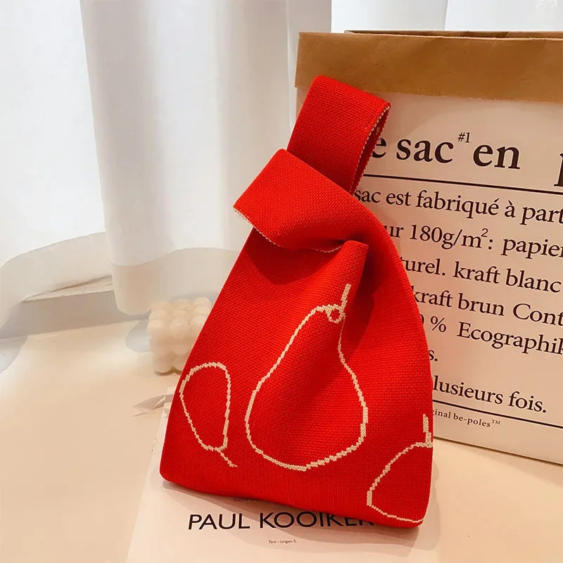 Red fabric bag with pear design on a white surface, with 'PAUL KOOIK' branding.
