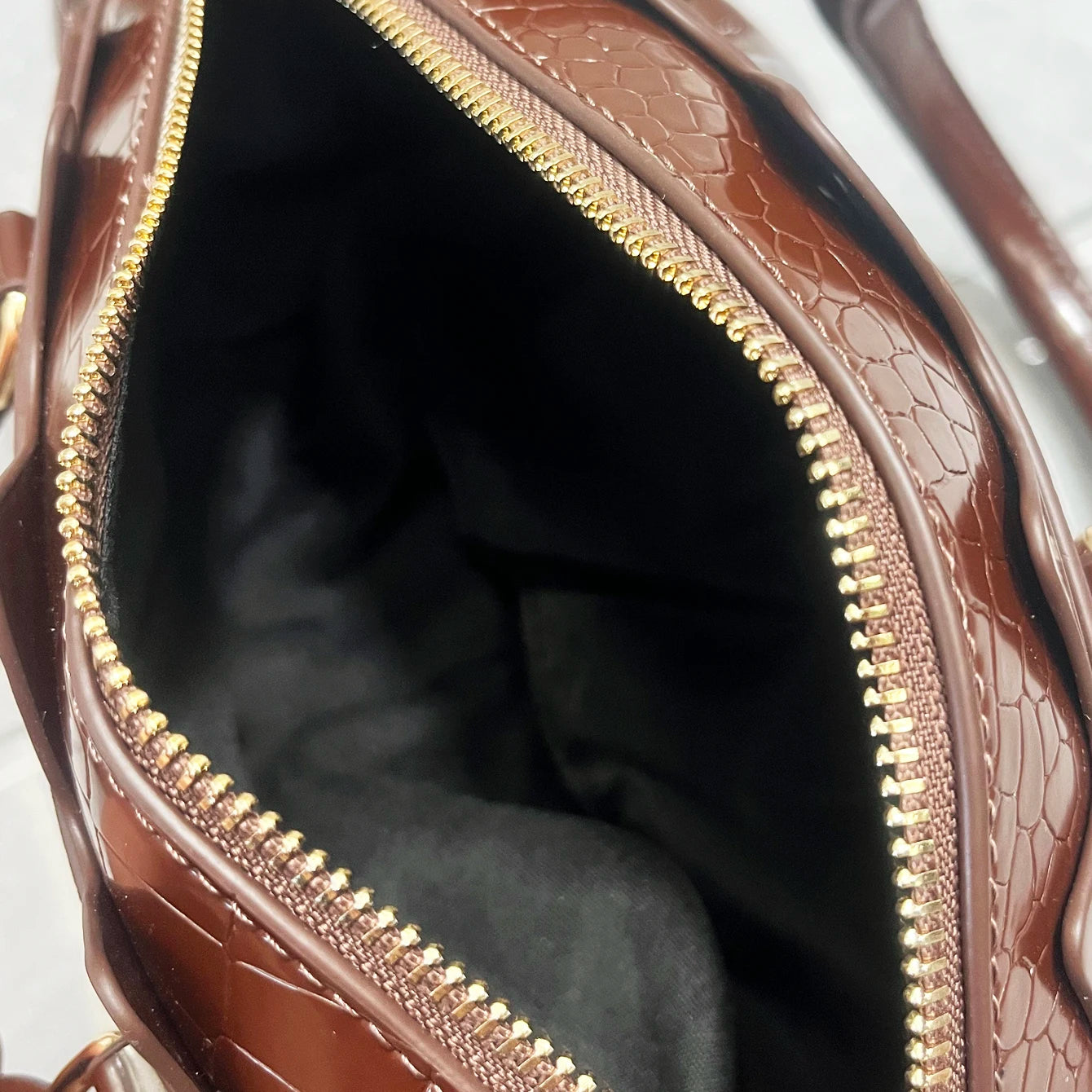 Close-up of a brown textured handbag with a gold zipper.