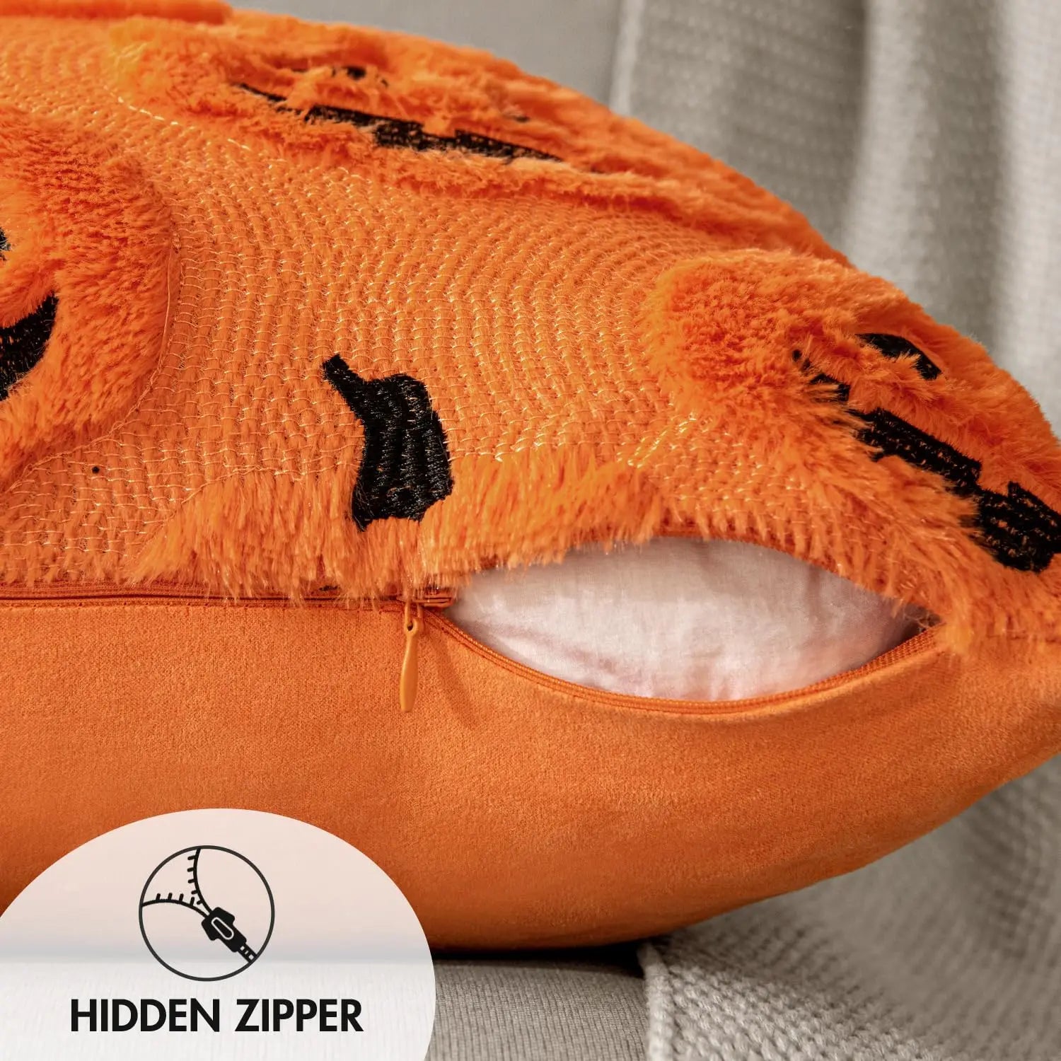 Close-up of an orange pillow with black accents and a hidden zipper label.